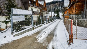 A snow-covered street with wooden houses and a signboard. - RentPlanet - Apartament Krzeptówki (Zakopane)