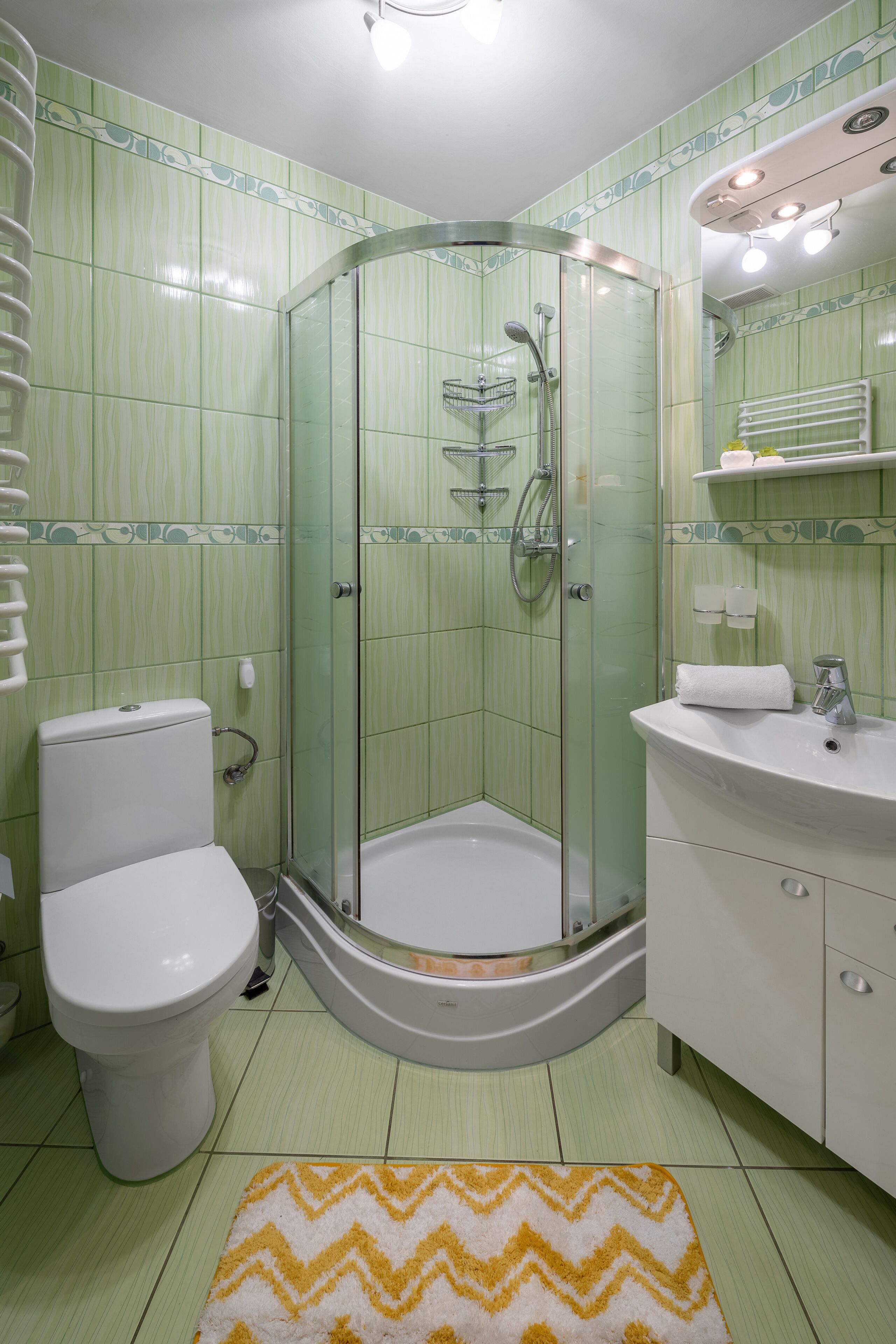 A bathroom with a glass-enclosed shower, a toilet, a sink, and a mirror.
