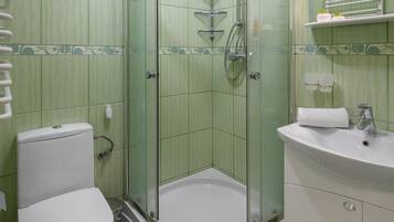 A bathroom with a glass-enclosed shower, a toilet, a sink, and a mirror.