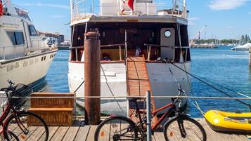 A docked boat with a wooden deck, a bicycle, and a life preserver.