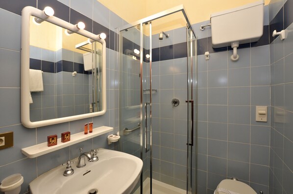 A bathroom with a glass shower enclosure, a sink with a mirror above it, and a toilet.