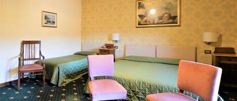 A hotel room with two beds, a chair, a nightstand, and a painting on the wall.