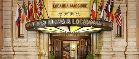 The entrance of the Grand Hotel Plaza & Locanda Maggiore with multiple flags and a classic architectural facade.