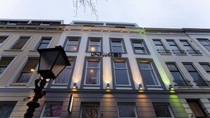 A building with the sign "UNPLUGGED" on the facade, featuring multiple windows and a street lamp in the foreground. - hotel emma next (Rotterdam)