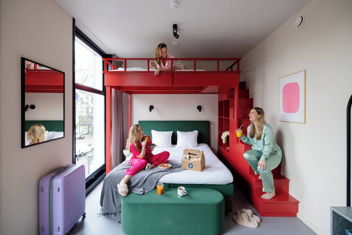 A room with a bunk bed, a suitcase, breakfast items, and a window with a view.