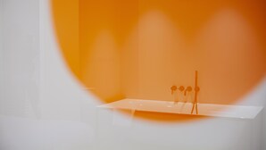 A minimalist room with a white reception desk and a large circular window. - hotel emma next (Rotterdam)