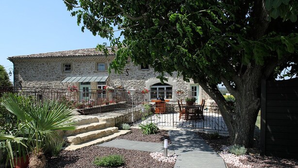 A stone building with a paved pathway leading to a wooden deck.