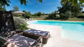 A poolside area with wicker furniture and a view of the pool.