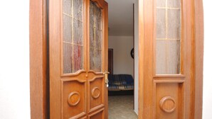 A wooden door with a glass panel and a room with a bed and a clock on the wall. - Apartment Ivanka (Kastela)