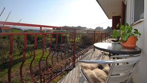 A balcony with a metal railing, a small round table with a potted plant, and a chair. - Apartment Ivanka (Kastela)