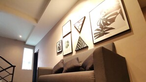 A modern living room with a grey sofa, a staircase, and framed artwork on the wall. - The Core Hotel (Subang Jaya)