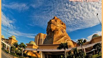 El centro comercial Sunway Pyramid con una gran estatua de león de piedra, palmeras y edificios circundantes.
