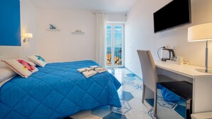 A hotel room with a bed, a desk, a TV, and a balcony with a view. - Caruso Sea View (Sorrento)