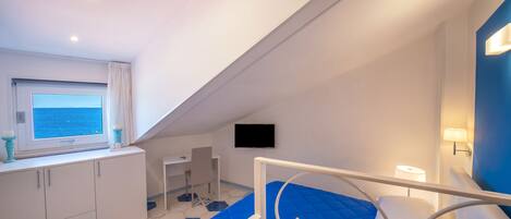 Ein Schlafzimmer mit einem Bett, einem Schreibtisch, einem Fernseher und einem Fenster mit Blick.
