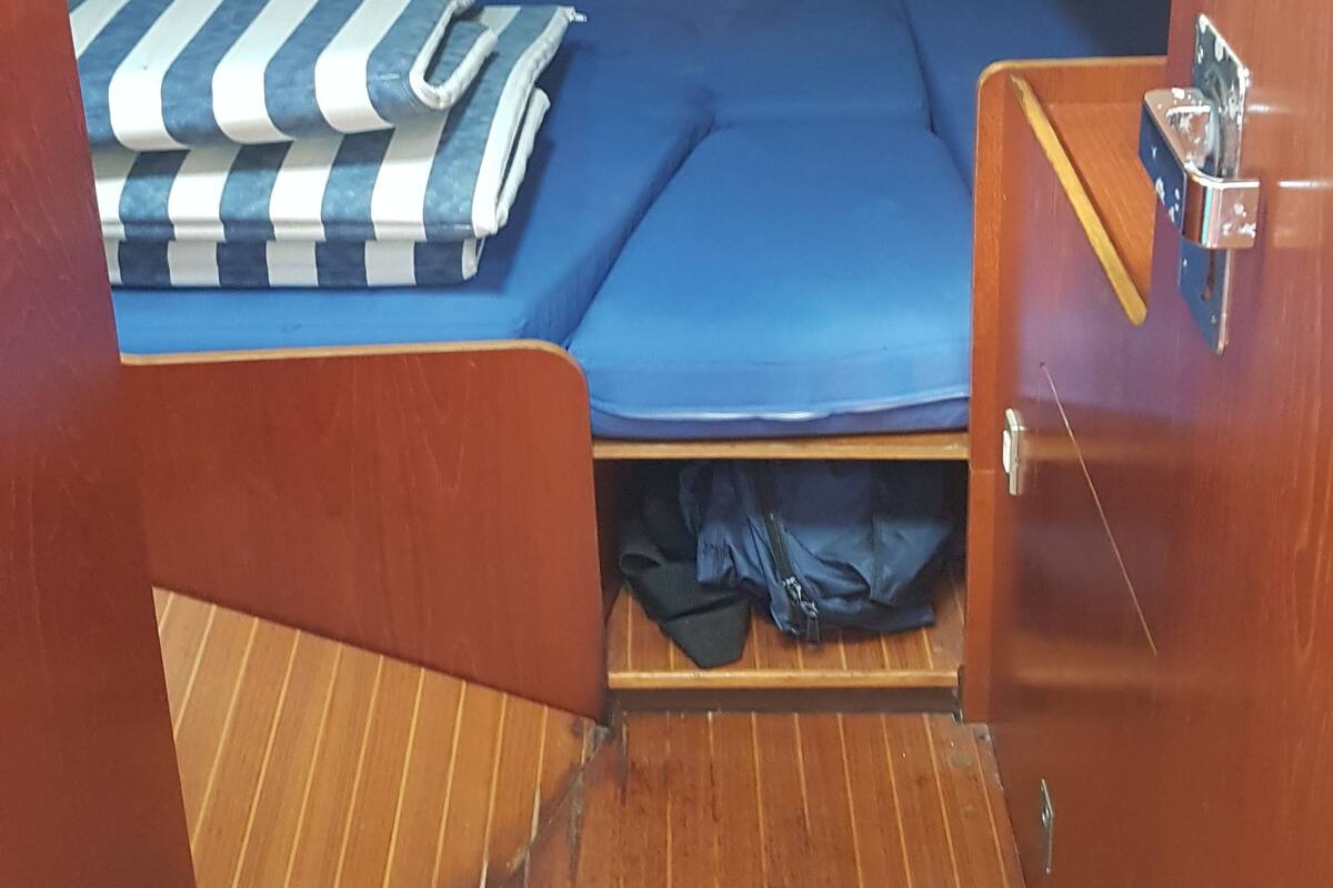 A compact cabin with a single bed, a small seating area, and a wooden floor.