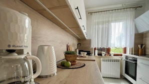 Una cocina moderna con cafetera, hervidor, planta en maceta y ventana con cortinas.