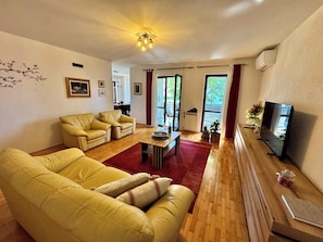 Een woonkamer met een bank, salontafel, televisie en open haard.