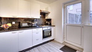 A modern kitchen with white cabinets, a microwave, toaster, and oven. - Walter Place (Edgware)