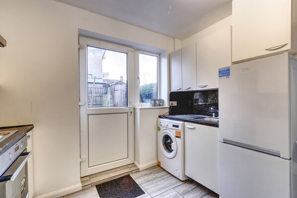 Una cocina compacta con lavadora, refrigerador y ventana.