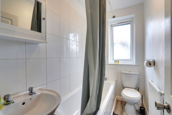 A bathroom with a white sink, a bathtub, a toilet, and a window. - Walter Place (Edgware)
