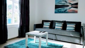 A modern living room with a grey sofa, a white coffee table, and a blue rug. - Walter Place (Edgware)