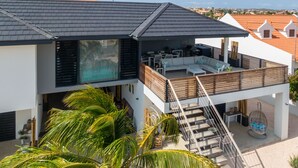 A modern two-story house with a balcony, outdoor seating area, and a staircase leading to the upper level. - Villa Hasta La Vista Royal (Jan Thiel)
