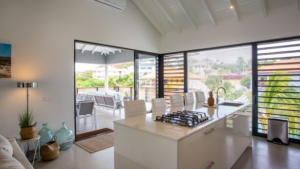 A modern kitchen with a central island, large windows, and a view of the outdoors. - Villa Hasta La Vista Royal (Jan Thiel)
