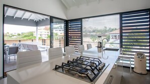 A modern kitchen with a gas stove, white countertops, and large windows offering a view of the outdoors. - Villa Hasta La Vista Royal (Jan Thiel)