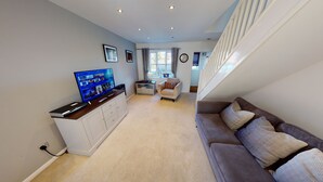 A living room with a flat-screen TV, a sofa, a chair, and a staircase. - Victoria House (Hull)