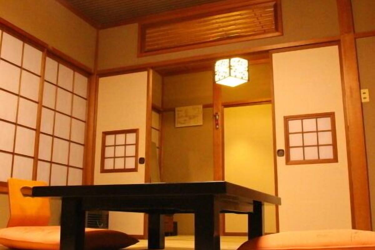A traditional Japanese room with tatami flooring, a low table, and sliding doors.