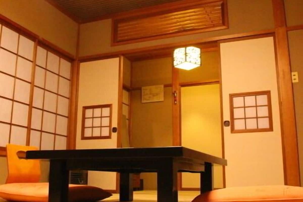 A traditional Japanese room with tatami flooring, a low table, and sliding doors.