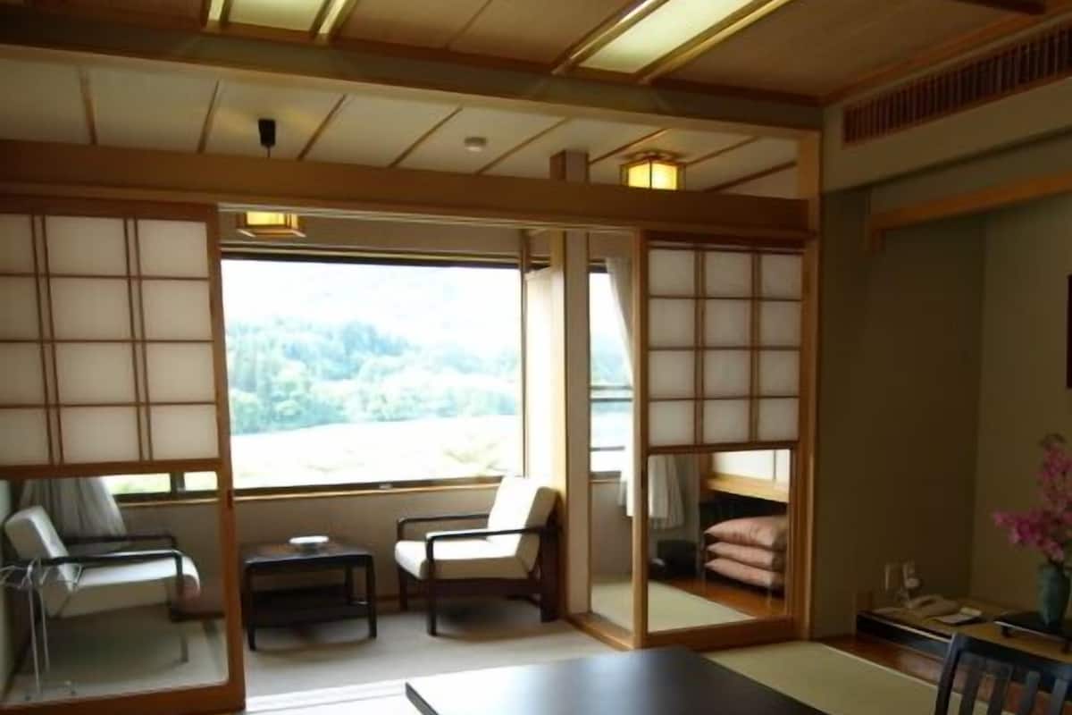 A traditional Japanese room with tatami flooring, a low table, and a view of a mountainous landscape.