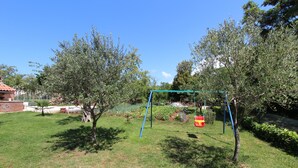 A grassy outdoor area with a swing set and trees. - Rooms Petra (Rovinj)