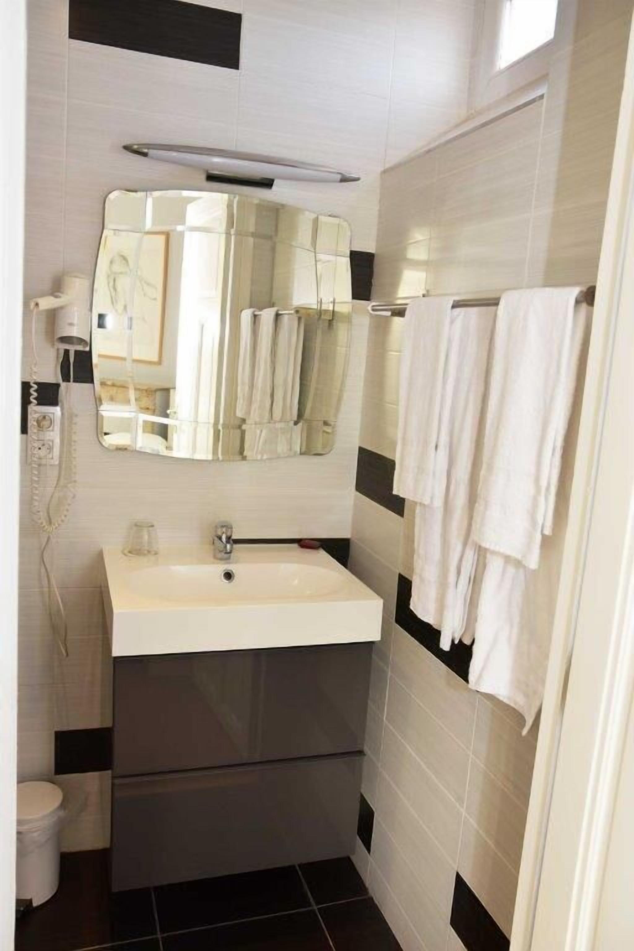 Un baño con un lavabo blanco, un espejo, un perchero para toallas y un inodoro.