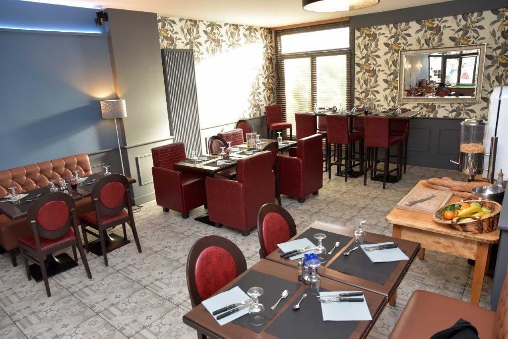 Una habitación de hotel con comedor, bar y zona de estar con sillas tapizadas en rojo.