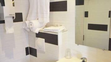 A modern bathroom with a white sink, a mirror, and a toilet.