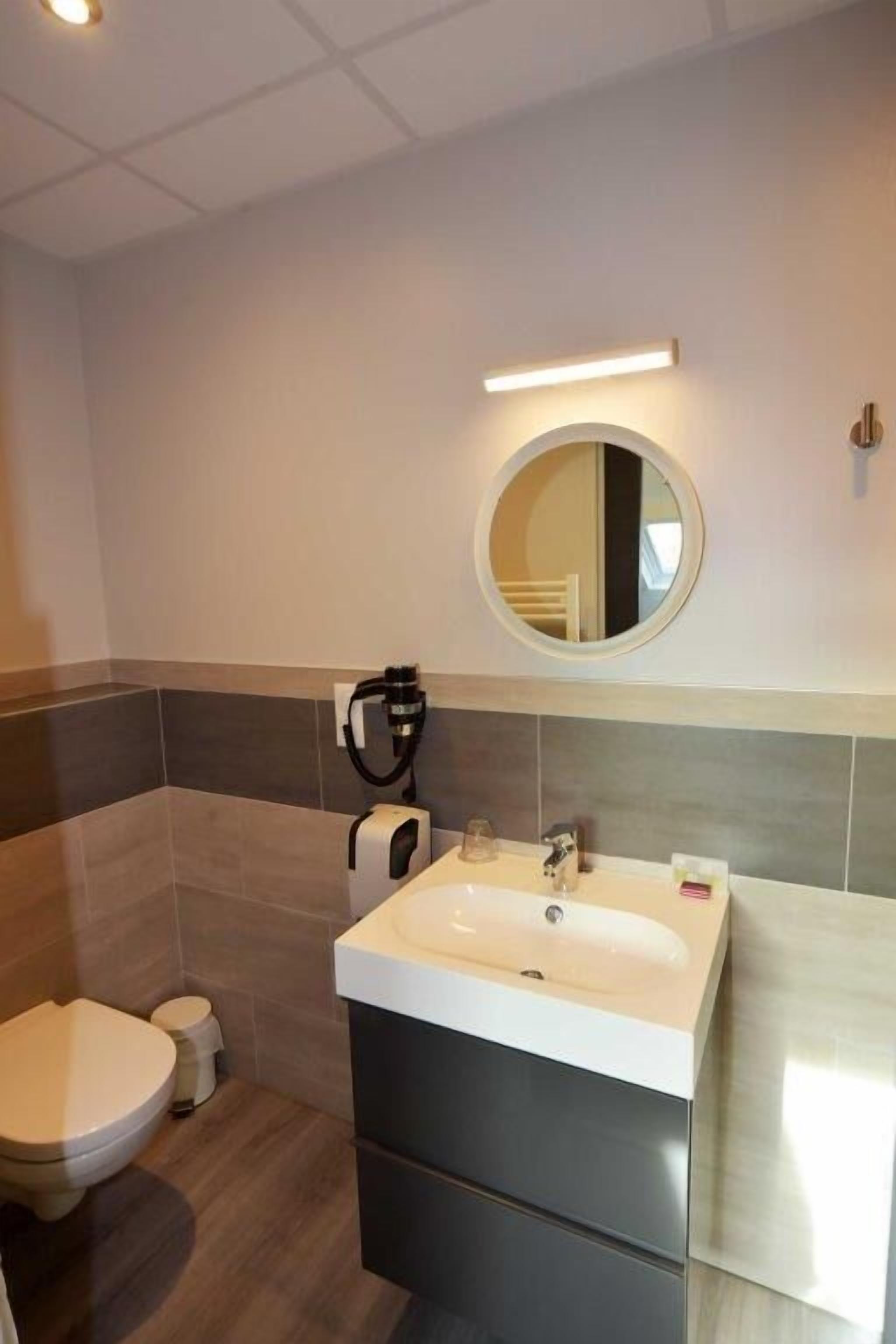A modern bathroom with a sink, mirror, and toilet.
