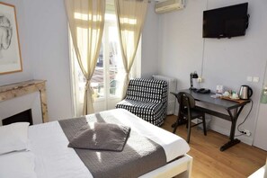 A hotel room with a bed, a desk, a chair, a television, and a window with curtains. - Hotel de Paris (Capdenac) (Capdenac-Gare)