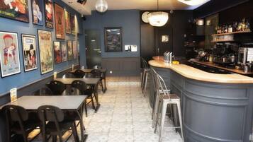 A bar area with a counter, stools, and a wall adorned with posters.