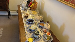 Una mesa dispuesta con diversos alimentos y condimentos, incluyendo tazones, cucharas y una botella de mostaza.