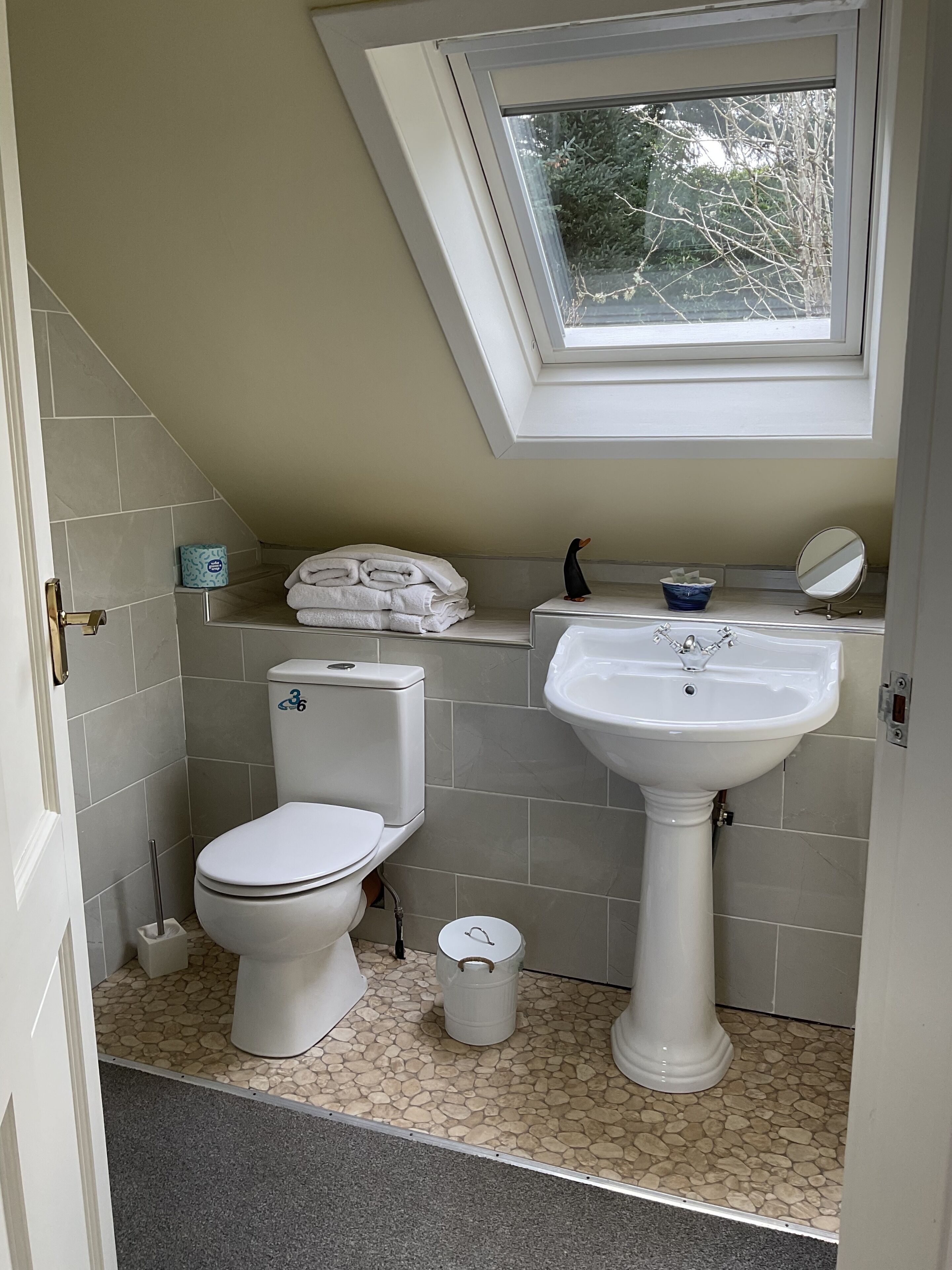 A bathroom with a toilet, sink, and a window above the sink.