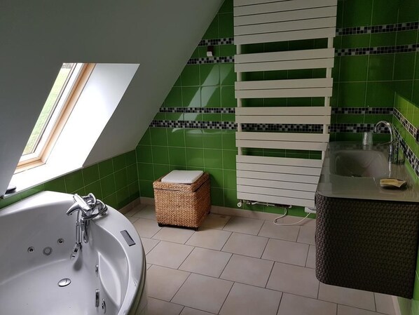 Un baño moderno con tragaluz, una bañera independiente, un taburete de mimbre y un lavabo empotrado.