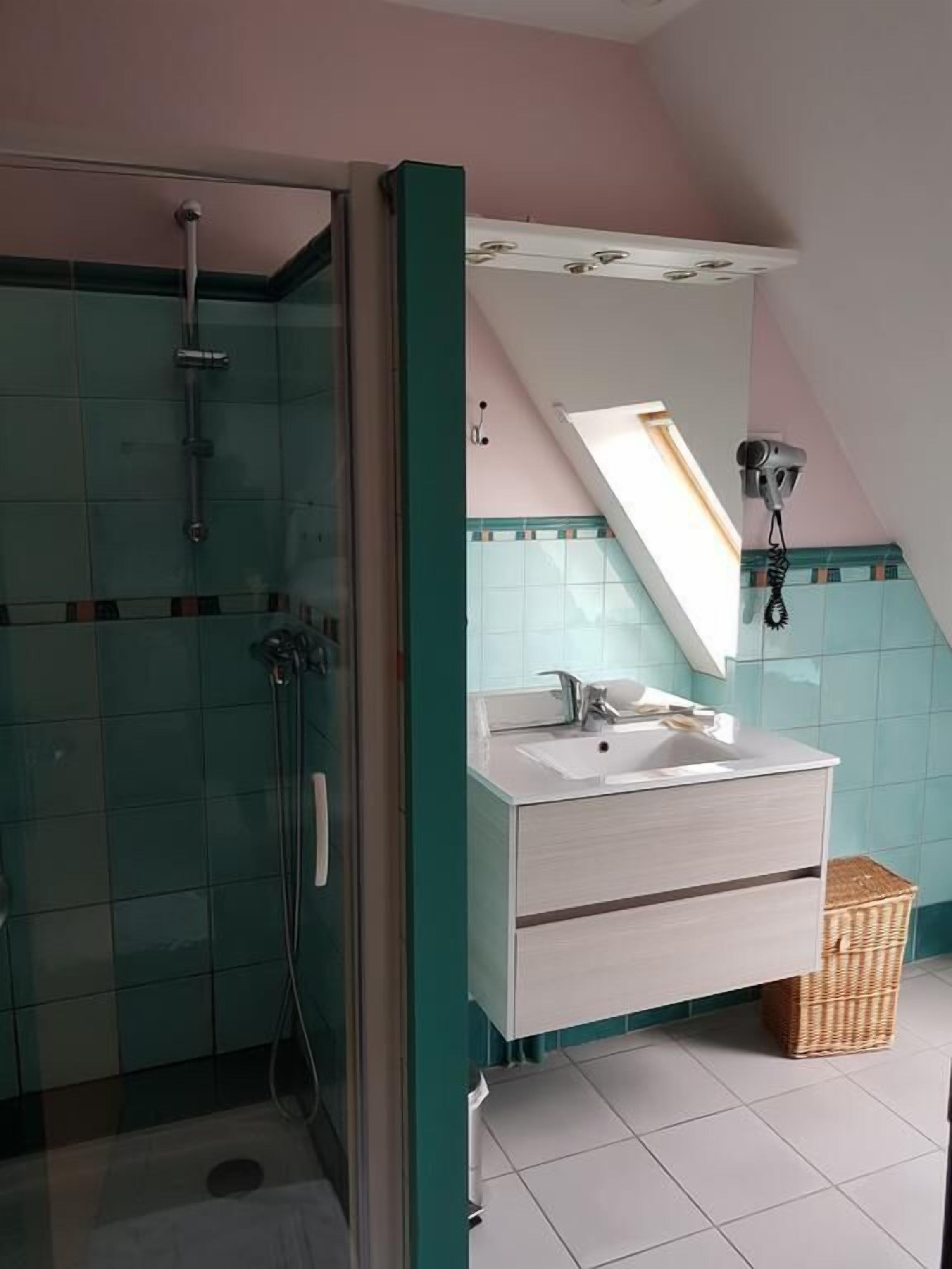 Un baño con ducha, lavamanos y espejo.