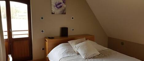 A bedroom with a bed, a wooden headboard, a door, and a window.