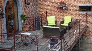 A brick building with a balcony, wicker furniture, and potted plants. - La Forge de l'Abbaye (Liessies)
