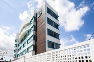 Un hotel moderno con fachada blanca, varios balcones y un letrero que indica que es un hotel.