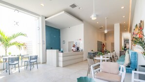 A spacious hotel lobby with a reception desk, seating area, and a view of the outdoors.