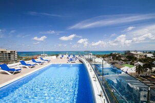Zona junto a la piscina con sillas reclinables azules y vista despejada del océano.