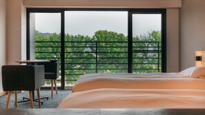 Une chambre d’hôtel avec une grande fenêtre, un lit, un bureau et une chaise.
