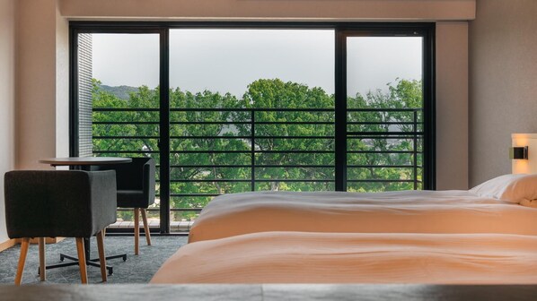 Una habitación de hotel con un ventanal grande, una cama, un escritorio y una silla.